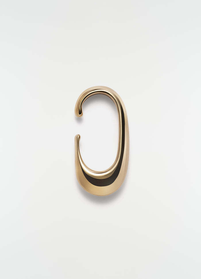 Long gold vermeil drop earcuff by LEMAIRE on plain white background close-up detail