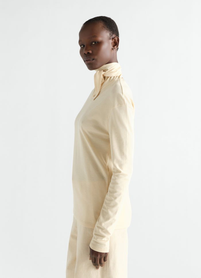 Long-sleeve scarf top in pale yellow silky jersey crepe by LEMAIRE worn by model side view