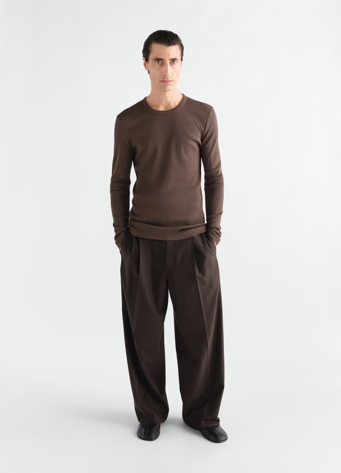Long-sleeve ribbed jersey top in brown worn by model with wide-leg trousers LEMAIRE front view
