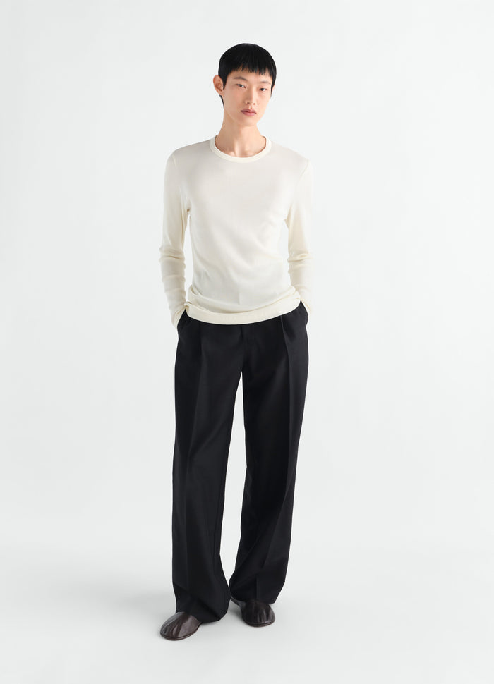 Long-sleeve ribbed jersey top in off-white LEMAIRE worn by model front view with black trousers and brown shoes