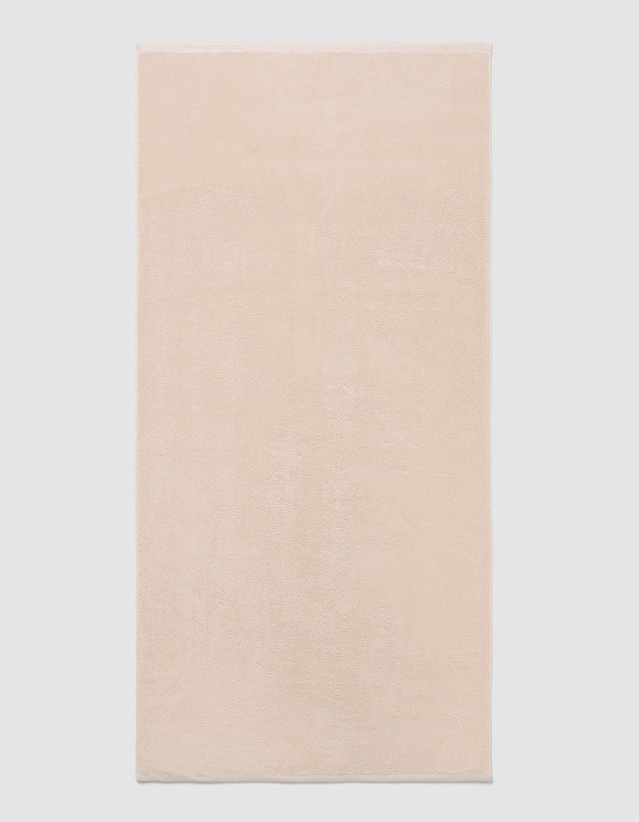 The Cozy Earth Loop Terry Bath Mat, a rectangular bath mat in light beige with a soft, plush texture, is displayed against a plain white background.|Color:Petal