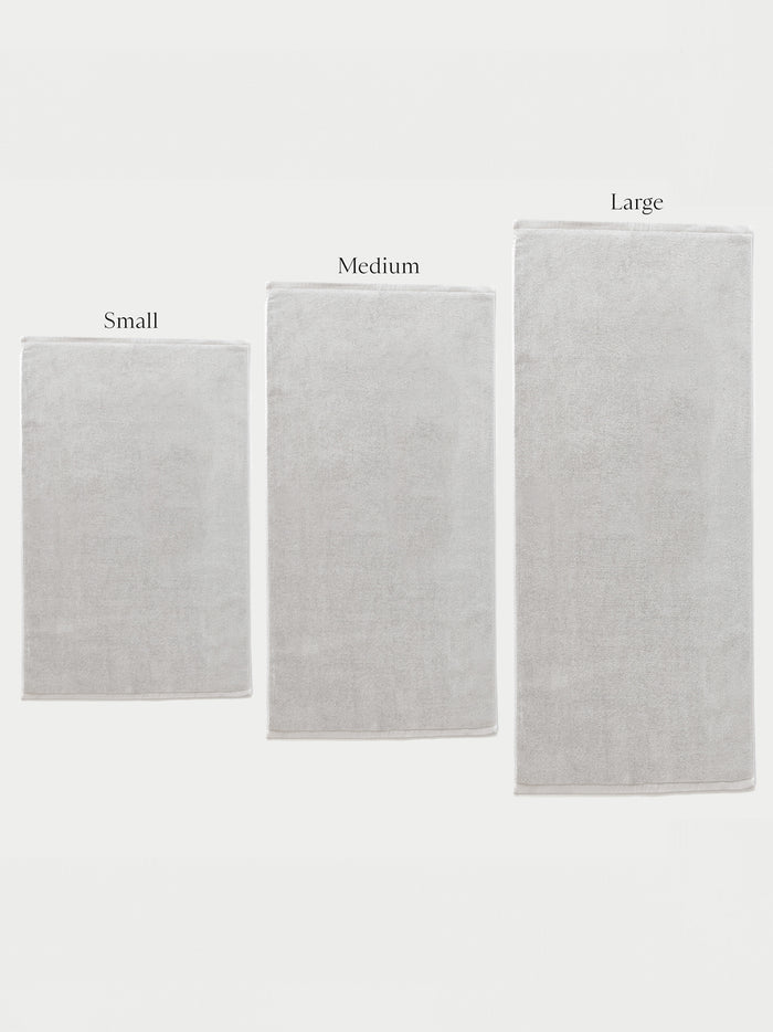 Three Cozy Earth Loop Terry Bath Mats in small, medium, and large are displayed side by side against a white background, each labeled above with its size.|Color:Light Grey