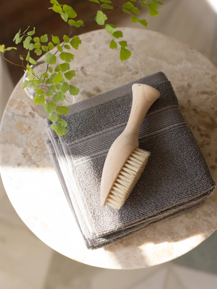 Charcoal washcloths folded on small table with brush |Color:Charcoal