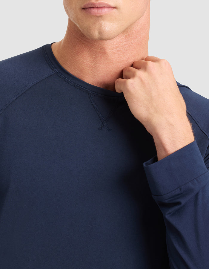 A man wears the Cozy Earth Men's Bamboo Stretch-Knit Long Sleeve in navy blue, with his fist near his collarbone. Only his lower face and upper torso are visible against a light gray background. |Color:Navy