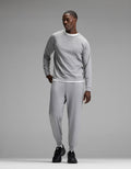 A man stands against a plain gray background wearing the Cozy Earth Men’s Brushed Bamboo Jogger Set in light gray, paired with black sneakers, looking to his left with one hand in his pocket.|Color:Stone