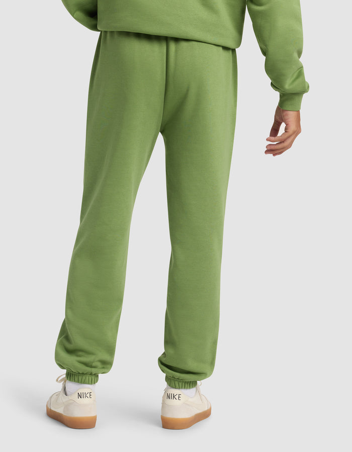 A person is shown from the back wearing Cozy Earth Men's Cityscape Sweatpant and a matching green sweatshirt, paired with white Nike sneakers with beige soles against a plain, light-colored background.|Color:Clover