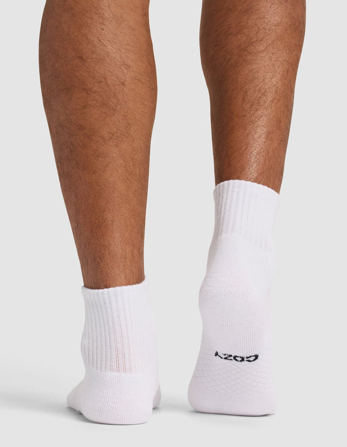 The image shows the back view of a person’s lower legs and feet wearing Cozy Earth Essential Quarter Socks in white. The right sock has "COZY" printed on the heel in black text, set against a plain white background.|Color:White