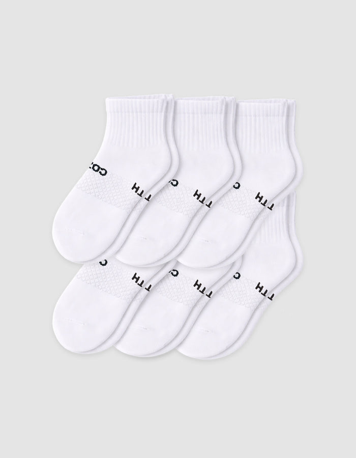 Six pairs of Cozy Earth Men’s Essential Quarter Socks in white are neatly displayed on a plain background, each featuring a ribbed cuff and black text by the toes. |Color:White