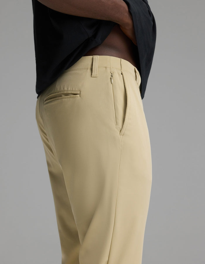 A man wearing Cozy Earth’s Men’s Everywhere Pant in light beige and a black shirt, shown from the side with hands in pockets against a plain gray background.|Color:Khaki