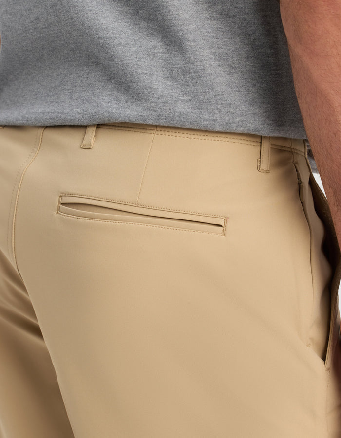 Close-up of a person wearing Cozy Earth Men's Everywhere Short in beige, featuring a back welt pocket, with a grey shirt; side and partial back view focuses on the waist and hip area.|Color:Sandalwood