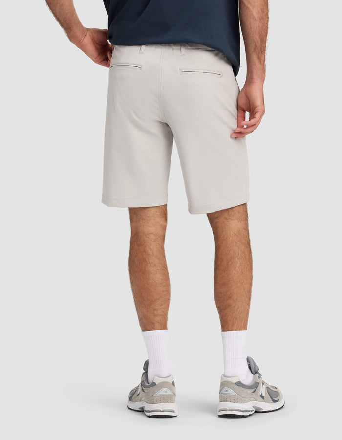 A person is shown from the back wearing Cozy Earth Men's Everywhere Shorts in light gray, paired with a dark shirt, white crew socks, and gray athletic shoes against a plain light background.|Color:Dew