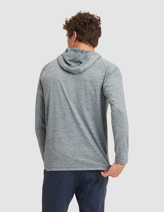 A man with curly hair, seen from behind against a white background, wears the Cozy Earth Men's Lightweight Performance Hoodie in light gray and navy pants. |Color:Heather Dawn
