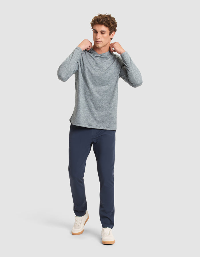 A man stands against a plain background, wearing the Cozy Earth Men's Lightweight Performance Hoodie. He looks to the side, holding the hoodie’s collar with both hands. |Color:Heather Dawn
