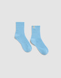The Plush Lounge Quarter Sock by Cozy Earth in light blue features a ribbed design and a small yellow tag on the upper edge, shown against a plain white background.|Color:Harbor