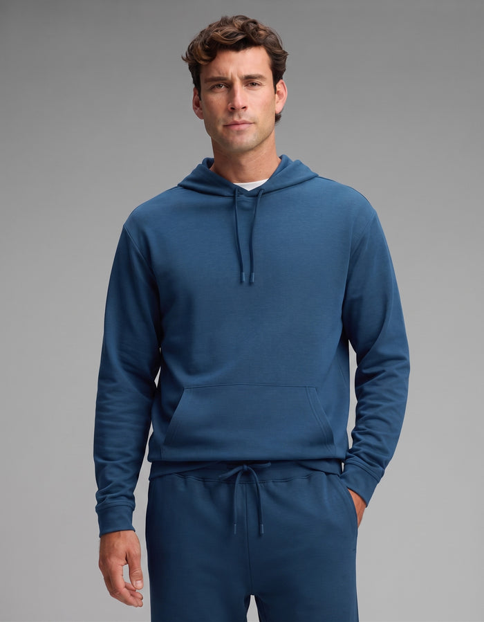 A man stands facing forward against a plain gray background, wearing the Cozy Earth Men's Versa Hoodie & Jogger Set in blue.|Color:Obsidian