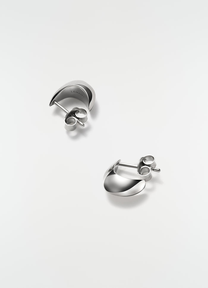 Micro silver drop earrings in polished metal by LEMAIRE on plain white background close-up detail