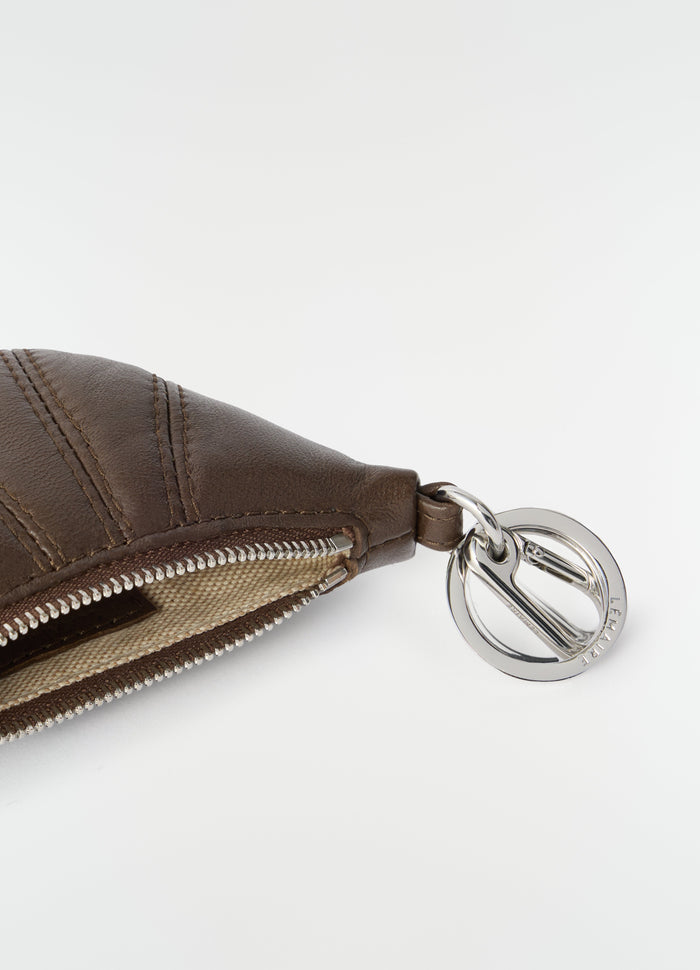 Mini brown leather croissant keyring with silver LEMAIRE logo charm close-up on white background