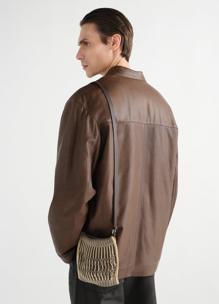 Mini crossbody filt net bag in beige and brown woven material worn by model with brown leather jacket LEMAIRE back view