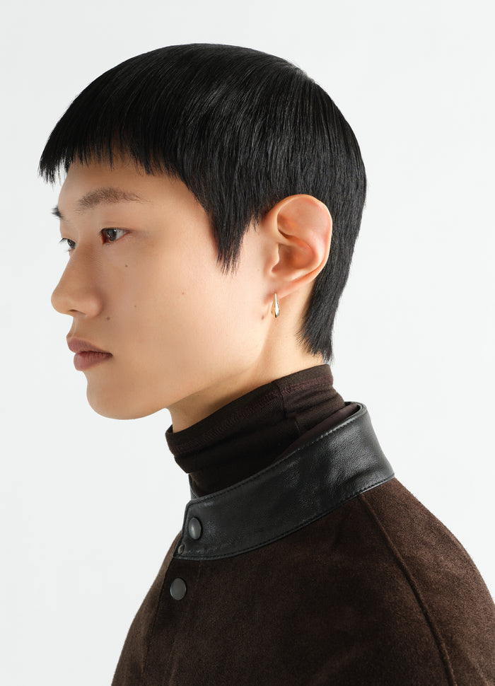 Mini drop earring in vermeil LEMAIRE worn by a model side view with black hair and brown jacket collar detail