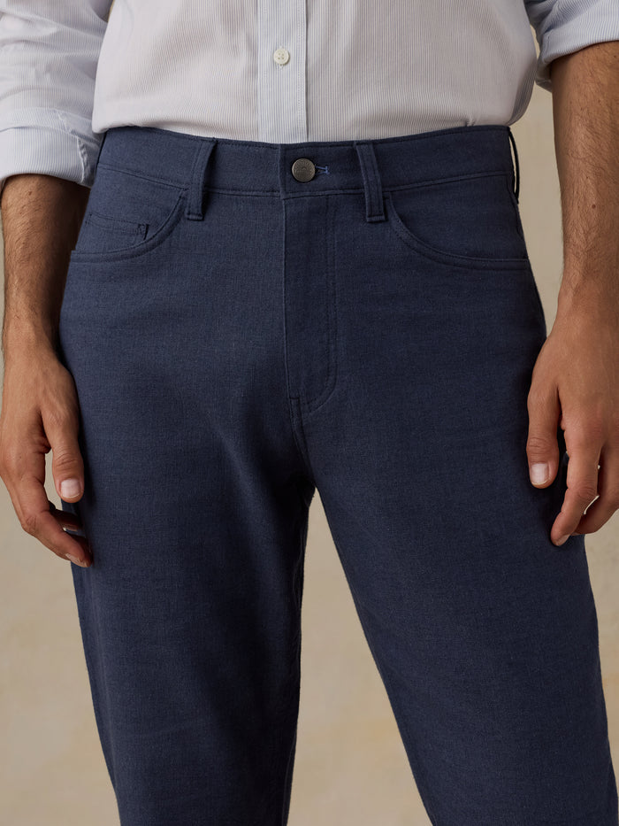 Man wearing a blue checkered shirt and navy pants on a beige background