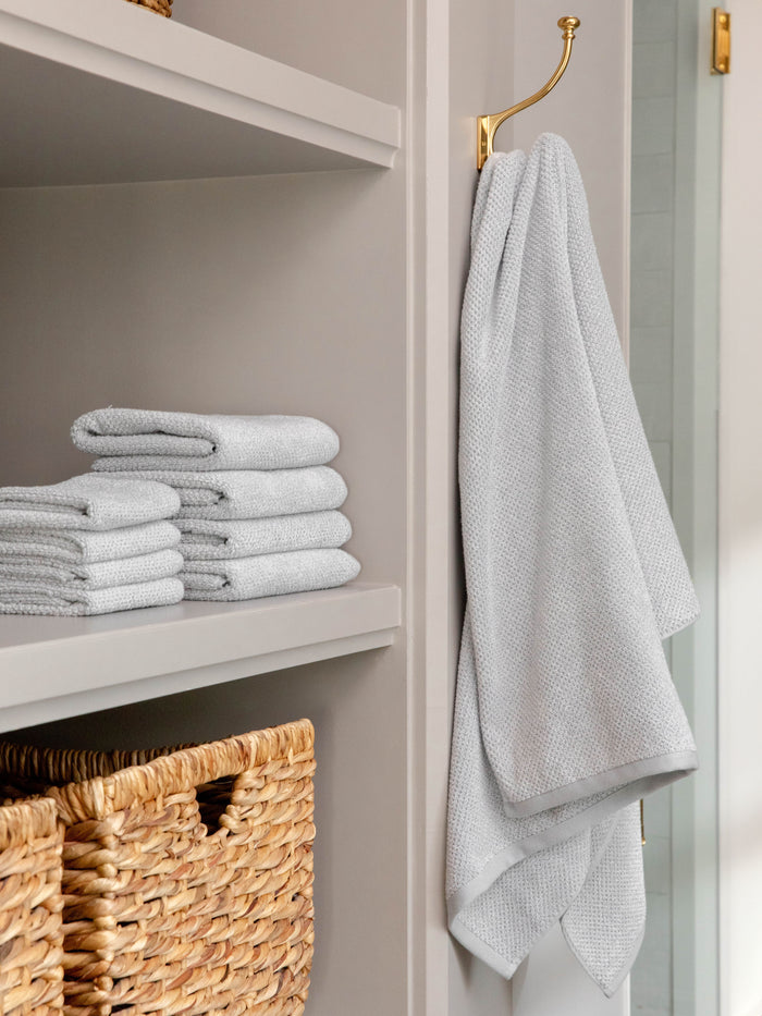 Nantucket Bath Sheets in the color Heathered Harbor Mist. Photo of Nantucket Bath Sheets taken as Nantucket hand towels, wash clothes, and bath towels are neatly placed on shelves in a bathroom. |Color: Heathered Harbor Mist