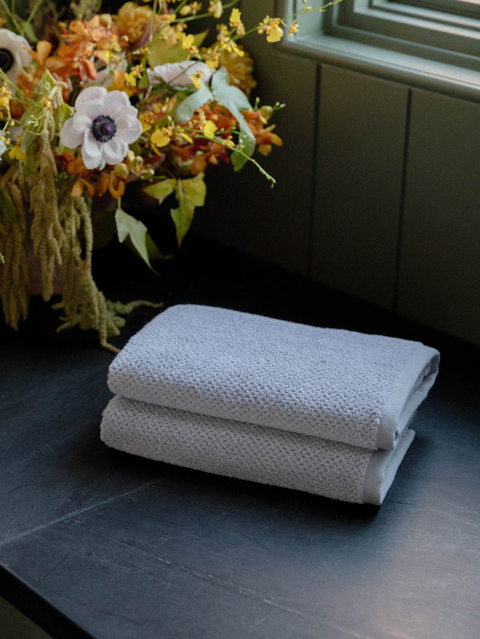 Nantucket Hand Towels in the color Heathered Harbor Mist. Photo of Nantucket Hand Towels taken with the bath towels resting on a countertop in a bathroom. |Color: Heathered Harbor Mist