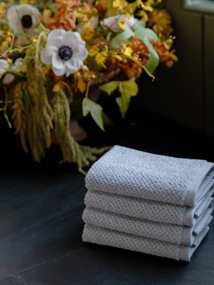 Nantucket Wash Cloths in the color Heathered Harbor Mist. Photo of Nantucket Wash Cloths taken with the Wash Cloths resting on a countertop in a bathroom. |Color: Heathered Harbor Mist
