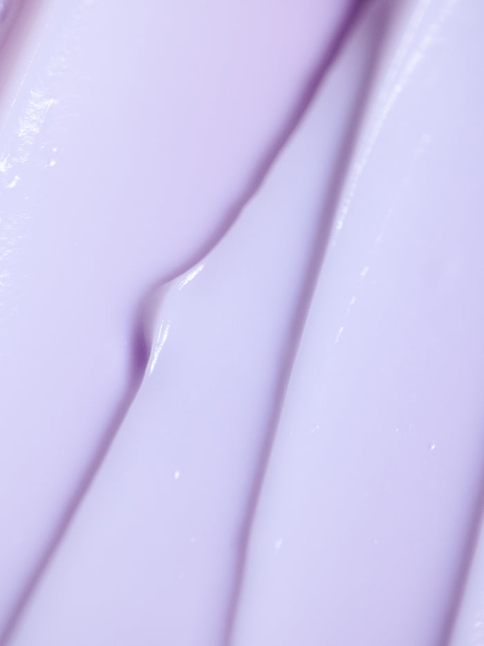 Close-up of Cozy Earth's Night Cream, showcasing its smooth purple texture with light reflections forming an abstract pattern of creamy ridges and folds. |Size:Full Size