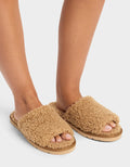 A person wears Cozy Earth’s Puffy Sheep Slides—fuzzy, tan open-toe slippers with thick, textured uppers and flat soles—standing on a white background.|Color:Fawn