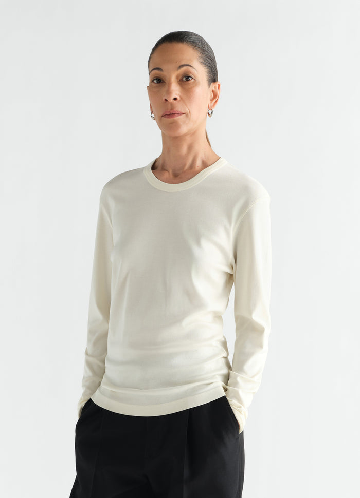 Rib long sleeve cream jersey top by LEMAIRE worn by model front view with hands in pockets
