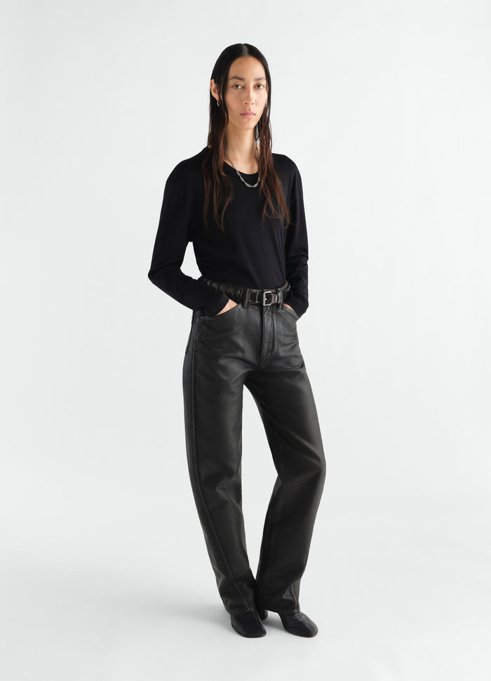 Rib long sleeve black jersey top by LEMAIRE worn by model with black leather pants on white background
