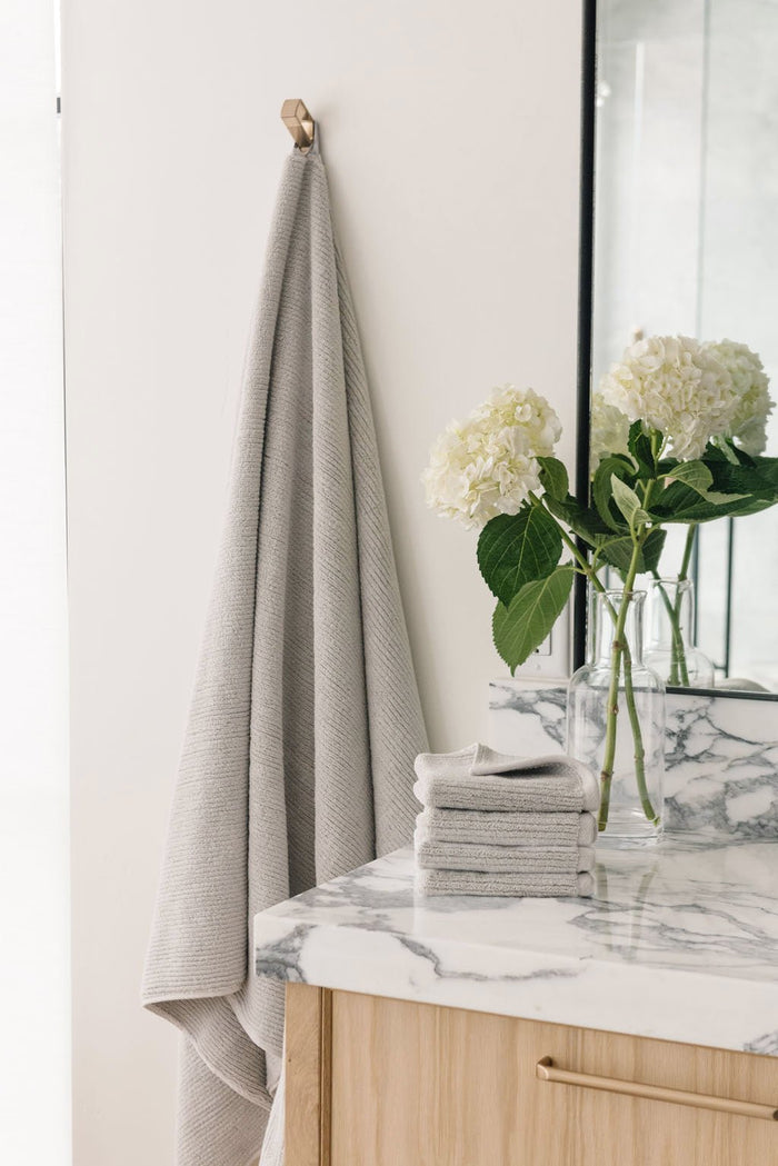 Ribbed Terry Bath Sheets in the color Light Grey. Photo of product taken in a bathroom next to a sink. |Color:Light Grey