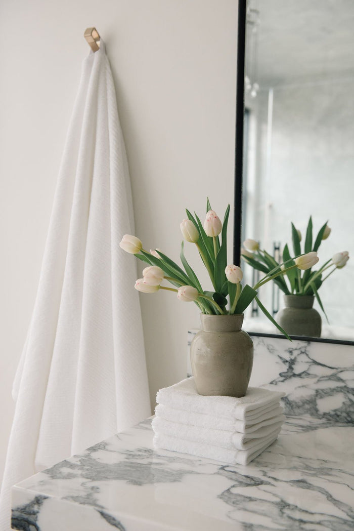 Ribbed Terry Wash Cloths in the color White. Photo of product taken in a bathroom featuring a white marble sink. |Color:White
