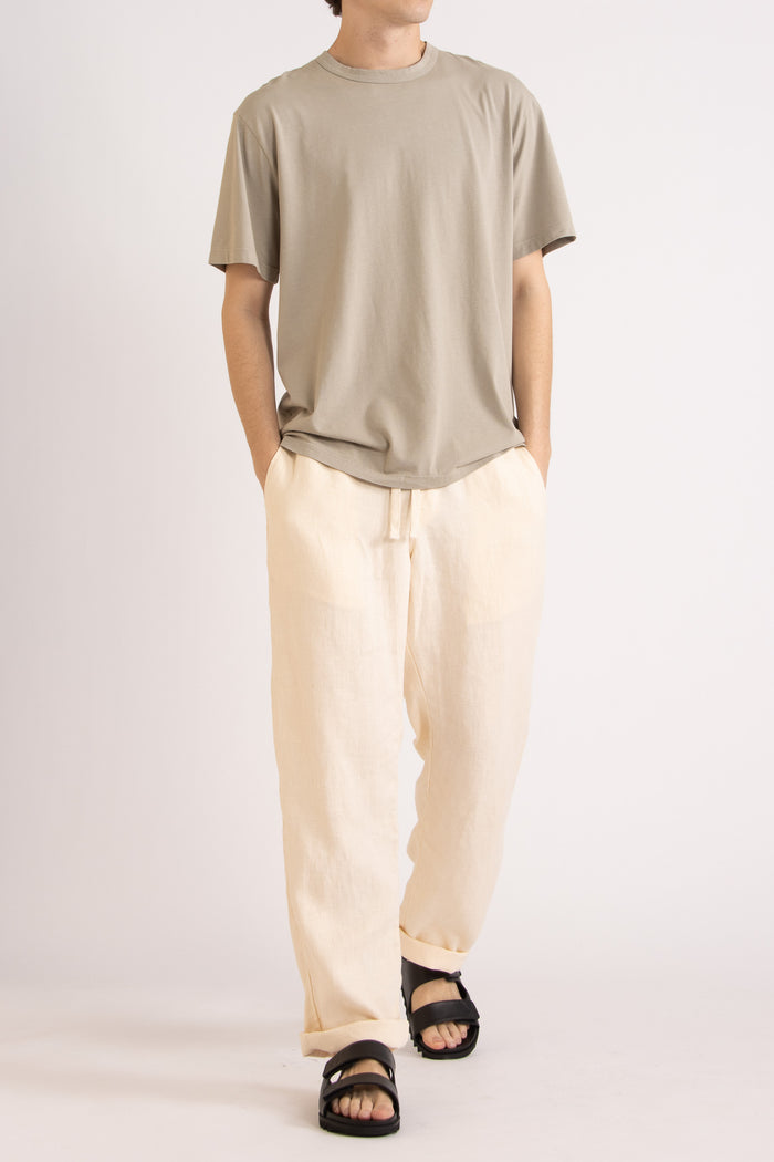 model wearing a oat cotton t-shirt and natural linen pants on a plain background, front view