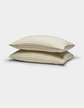 Two Cozy Earth Soft-Wash Cotton Pillowcases in beige with thin horizontal brown stripes are stacked against a plain white background.|Color:Coconut and Sandalwood Stripe