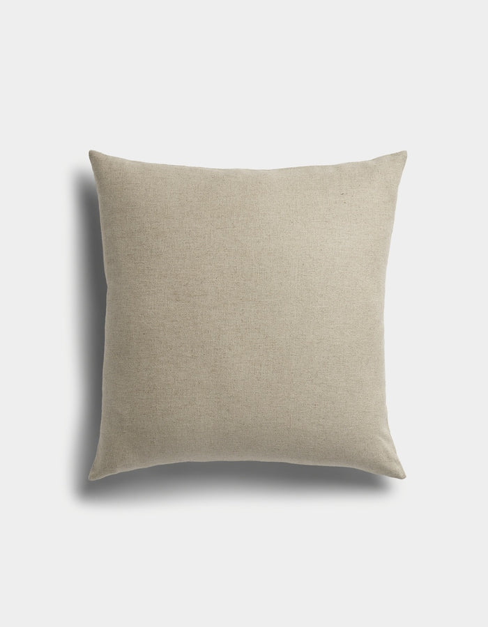 The Sonoma Throw Pillow by Cozy Earth is a square beige cushion with a plain fabric cover, displayed against a white background featuring a faint shadow on the left side.|Color:Tallow|Size:24" x 24"