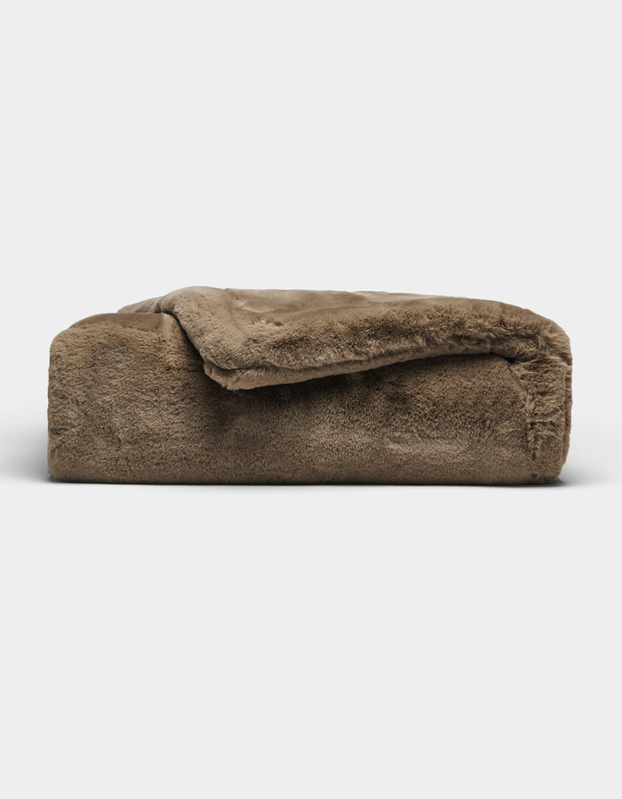 The Cozy Earth Cuddle Blanket, featuring a plush brown fabric and soft, fuzzy texture, is shown folded against a plain white background.|Color:Walnut