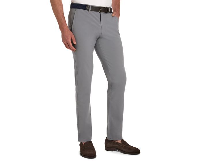 Man wearing The Anson Chino Pant in light gray with a black belt and dark brown loafers, showcasing wrinkle-resistant, quick-dry, eco-friendly fabric with four-way stretch.