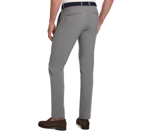 The Anson Chino Pant: Light Gray, slim-fit trousers with slant pockets, worn with a white shirt, dark belt, and brown loafers, showcasing wrinkle-resistant performance fabric.