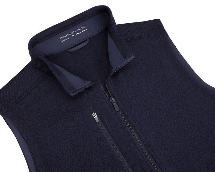 The Ashby Vest: Heathered Dark Navy by Holderness & Bourne, featuring a zip-up design, zippered chest pocket, and brushed interior for comfort and style.