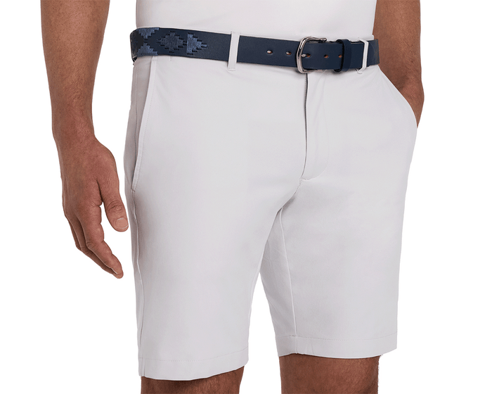 The Barker Belt: Navy & Slate, featuring geometric stitching, complements light-gray tailored shorts. Right hand casually rests in pocket, showcasing craftsmanship.