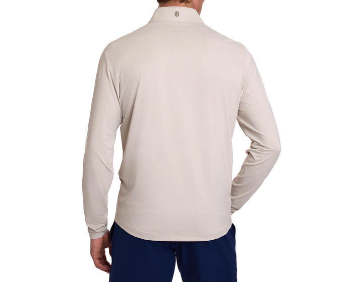 Back view of The Bell Quarter-Zip: Heathered Dune, showcasing its light-beige long sleeves and small logo on the collar, styled with dark navy trousers.