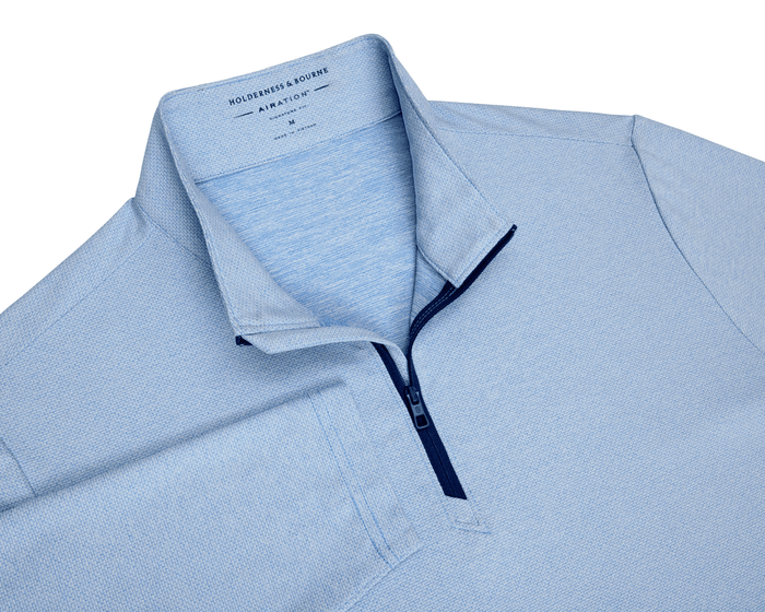 The Bell Quarter-Zip: Heathered Vista Blue features a textured knit, navy quarter-zip, discreet chest pocket, and modern drop-tail silhouette for versatile, sporty sophistication.