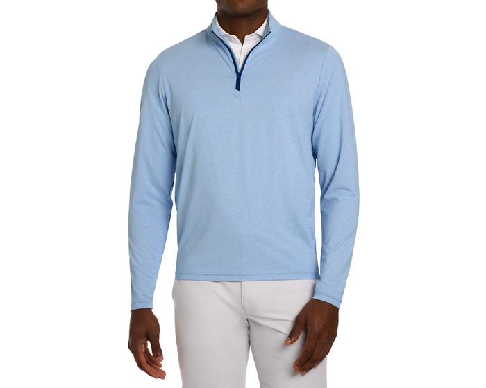 The Bell Quarter-Zip: Heathered Vista Blue, worn over a white collared shirt with light-gray trousers, features a modern drop-tail silhouette and sporty sophistication.