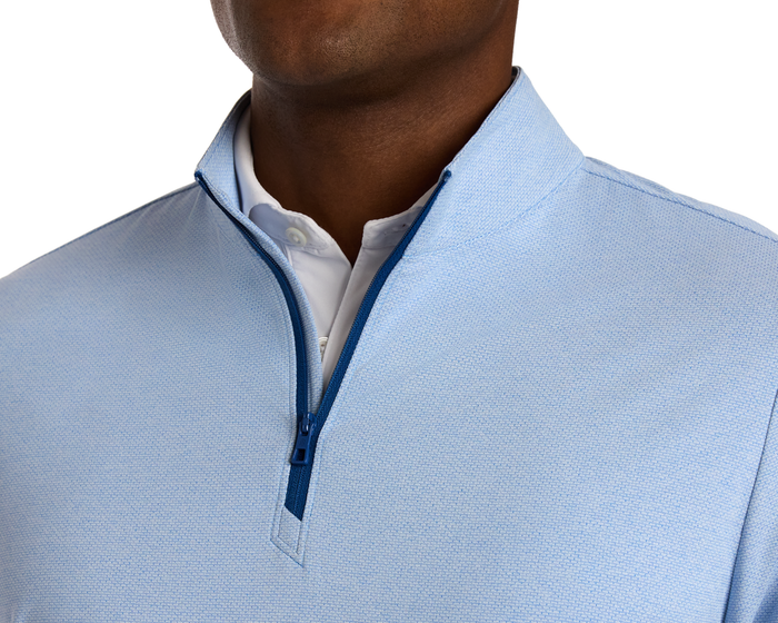 The Bell Quarter-Zip: Heathered Vista Blue pullover with light-blue texture and navy zipper over a white shirt, offering a modern, sporty look.