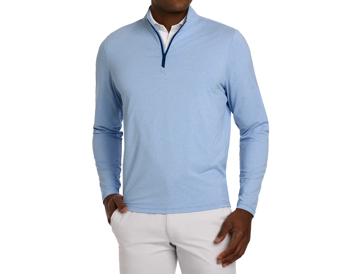 Person wearing The Bell Quarter-Zip: Heathered Vista Blue over a white collared shirt, showcasing its lightweight, breathable fabric and modern drop-tail silhouette.