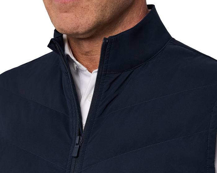 Man wearing The Benton Vest: Navy, showcasing its quilt-patterned front and two-way zipper over a white collared shirt, emphasizing comfort and mobility.