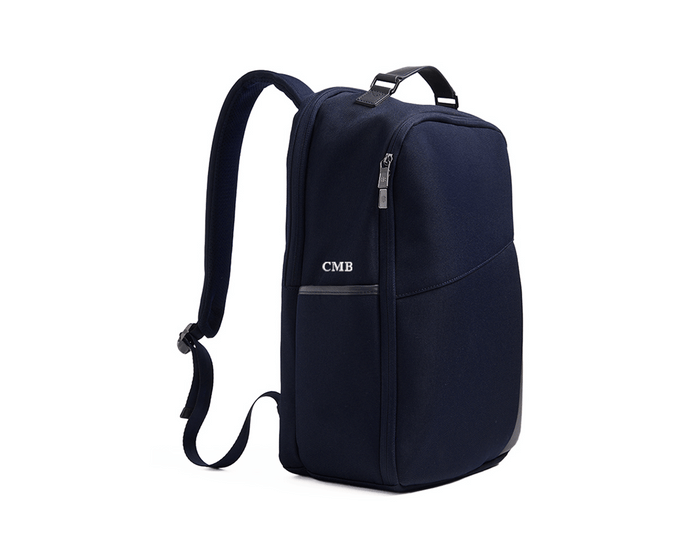The Broughton Backpack: Navy Ballistic - White Embroidery, featuring a side view with adjustable straps, top handle, and visible CMB initials on the side pocket.