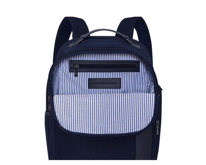 The Broughton Backpack: Navy Ballistic, features an unzipped front pocket revealing a striped lining, zippered inner pocket, and leather patch stamped “HOLDENNESS & BOURNE.”