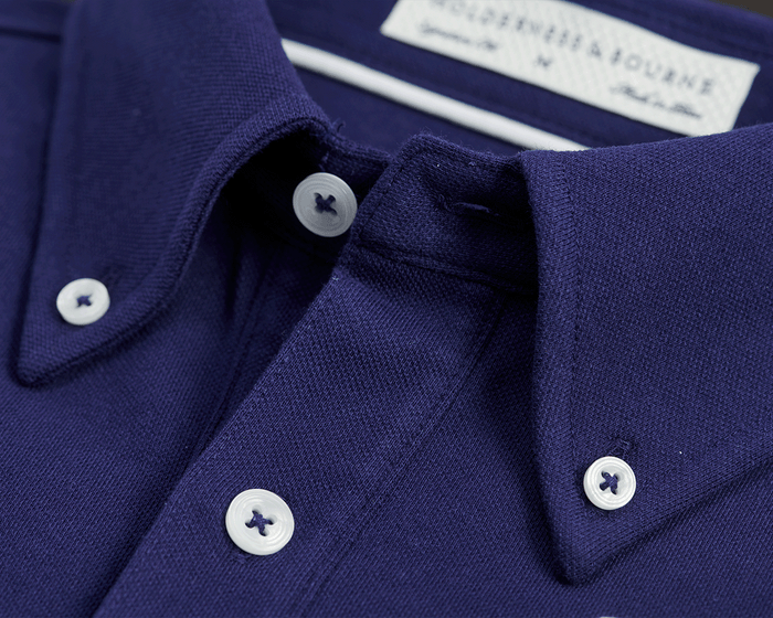 The Burton Shirt: Navy, featuring a detailed close-up of the button-down collar with visible white buttons and textured pique knit fabric.